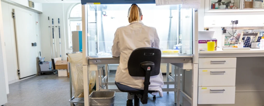 Researcher sitting and working with lab equipment in lab.